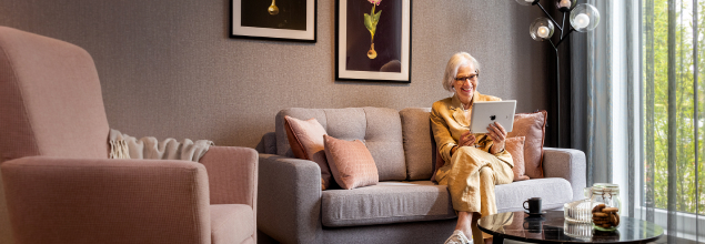 Ältere Dame auf der Couch im Wohnzimmer am lesen