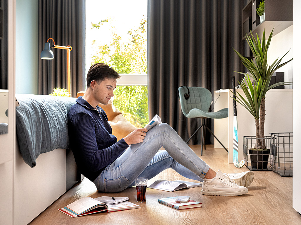 Student sitzt auf dem Boden und lernt in einer Studentenwohnung