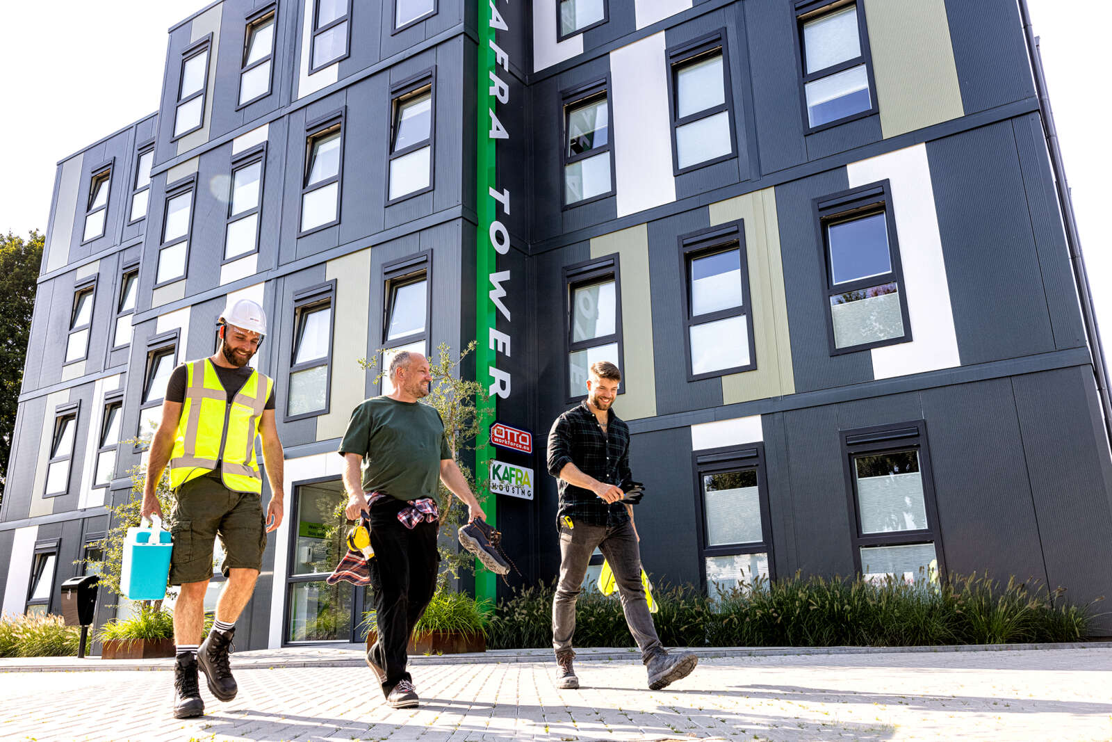 Construction workers walk in front of the Kafra Tower